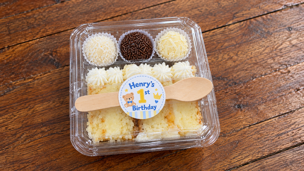 Closed first birthday cake box with personalized sticker and wooden spoon