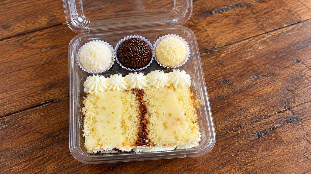 Open individual cake box with cake slice and three sweets for a first birthday party